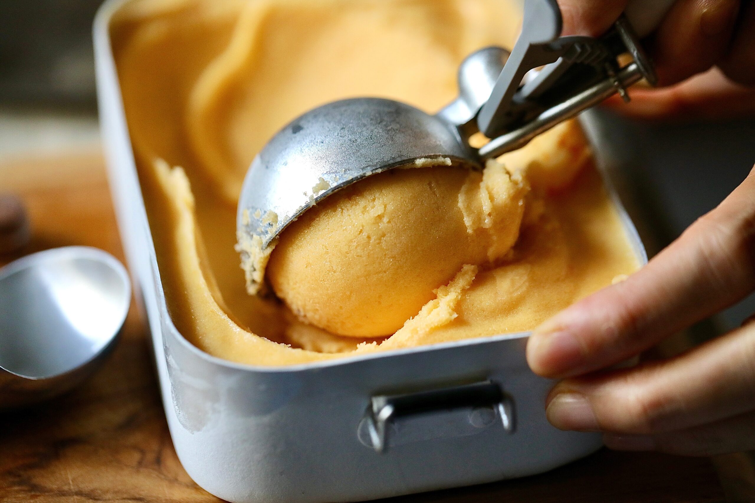 A,Hand,Uses,An,Ice,Cream,Scoop,To,Serve,A