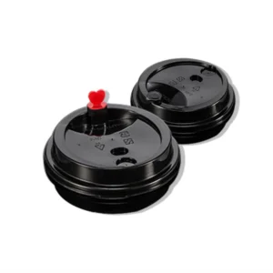 Two black disposable coffee cup lids, one with a small red heart-shaped stopper on top