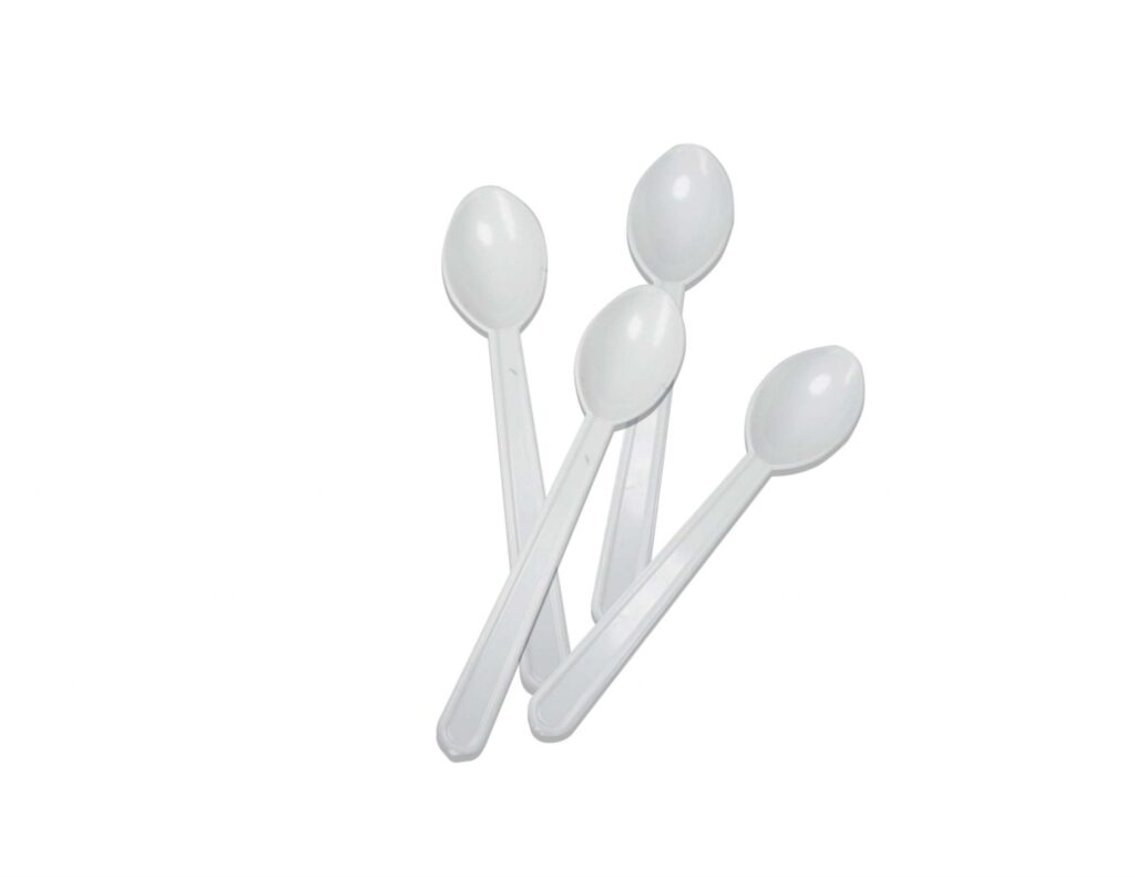 Four white plastic disposable spoons arranged in a fan shape.
